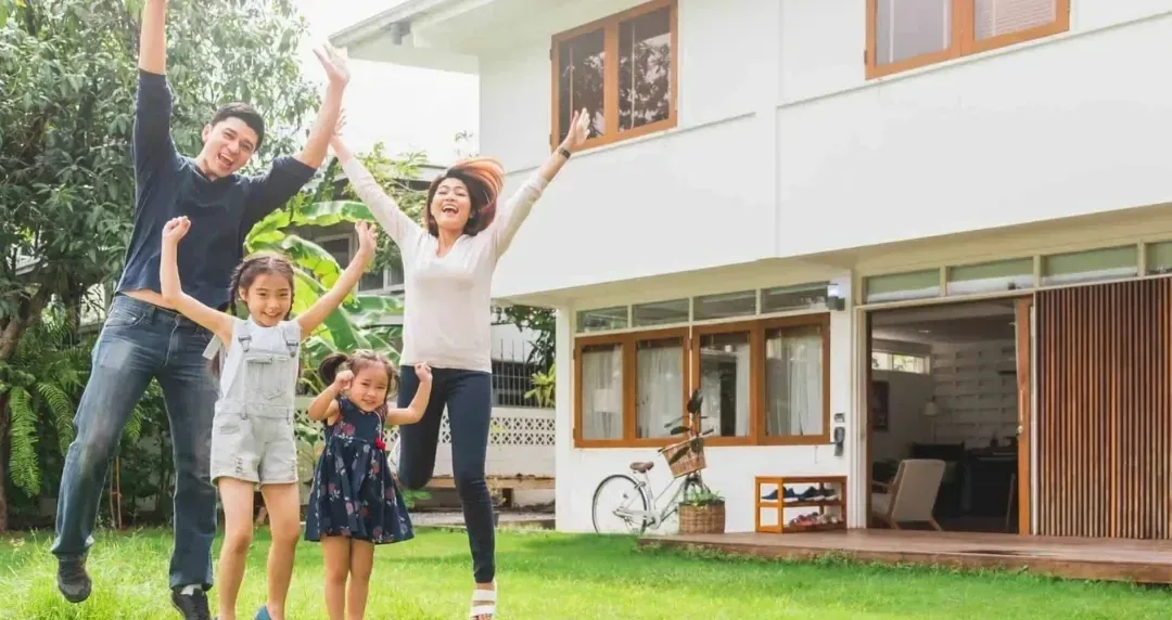 A family celebrating on the lawn in front of their new house